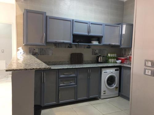 cocina con armarios azules y lavadora en Ramco For Furnished Apartments And Accommodation Compound Leila en El Cairo