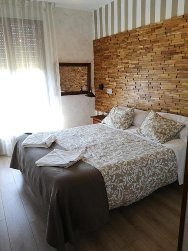 a bedroom with a large bed and a brick wall at Hostal Juan Bravo in Segovia