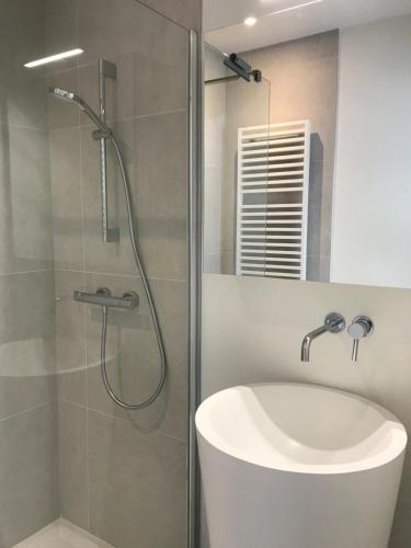 a bathroom with a shower with a tub and a sink at Zilverzand aan zee - frontaal zeezicht in Koksijde