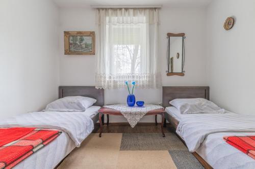 una habitación con 3 camas y una mesa con un jarrón. en Frile Apartments, en Nikšić