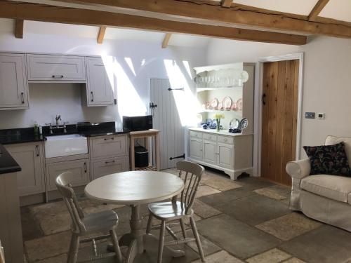 a kitchen and living room with a table and chairs at Courtyard Cottage in Stroud