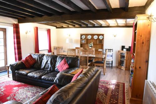 a living room with a leather couch and a dining room at Ty-Gwyn Cottage in Clynnog-fawr