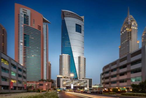 a tall building in a city with tall buildings at Staybridge Suites Dubai Internet City by IHG in Dubai