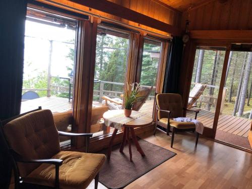 sala de estar con mesa, sillas y ventanas en Beautiful 3 Bed Cottage in Ytteroy with seaview, en Ytteroy