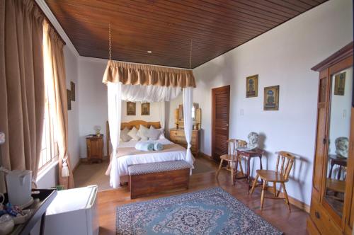 a bedroom with a bed and a table and chairs at Knysna Manor House in Knysna