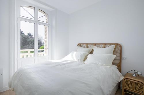 a white bed with white sheets and a window at La Perle Marine - Bow-Window vue mer in Dinard