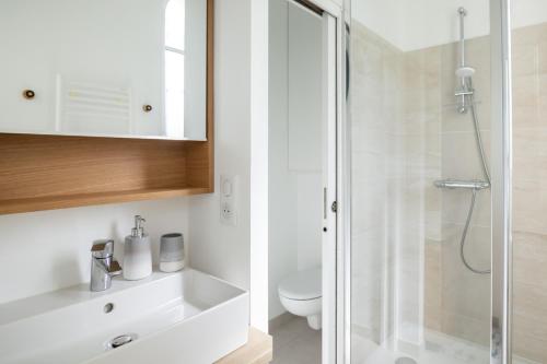 a white bathroom with a shower and a toilet at La Perle Marine - Bow-Window vue mer in Dinard