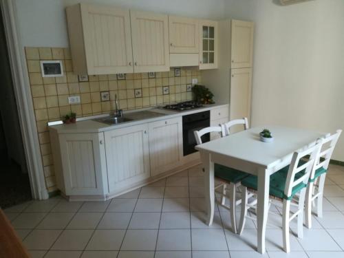 a kitchen with white cabinets and a table and chairs at La casa di Via Defferrari in Noli