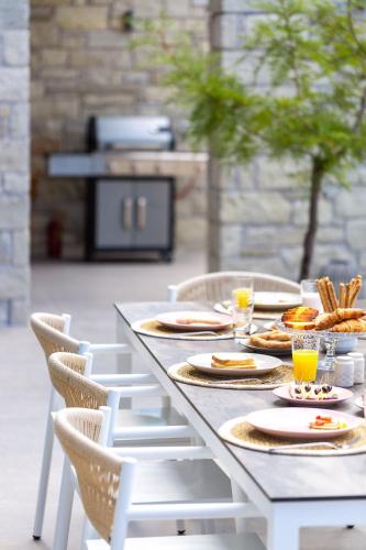 a table with plates of food and drinks and chairs at Sissy Luxury Villa Chania in Plataniás