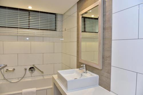a white bathroom with a sink and a mirror at La Lucia Sands Beach Resort in Durban