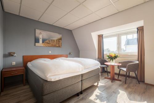 a bedroom with a bed and a table and a window at Hotel Astoria in Noordwijk aan Zee