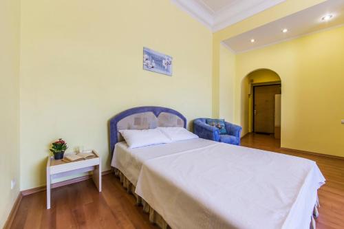a bedroom with a large bed and a blue chair at Однокімнатні апартаменти на Майдані, дистанційне заселення 24х7 in Kyiv