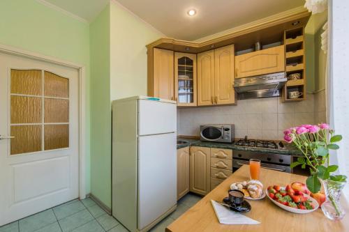 a kitchen with a refrigerator and a bowl of fruit on a table at Однокімнатні апартаменти на Майдані, дистанційне заселення 24х7 in Kyiv