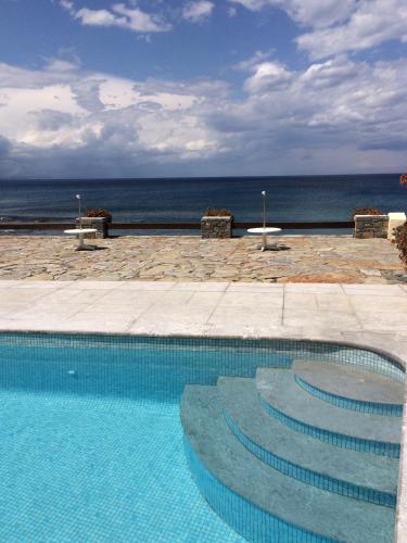 a swimming pool with stairs in front of the ocean at Porto Sisi Hotel Apartments in Sissi