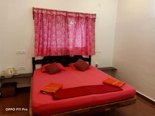 a bedroom with a red bed with a pink curtain at Namaste Yoga Farm in Gokarna