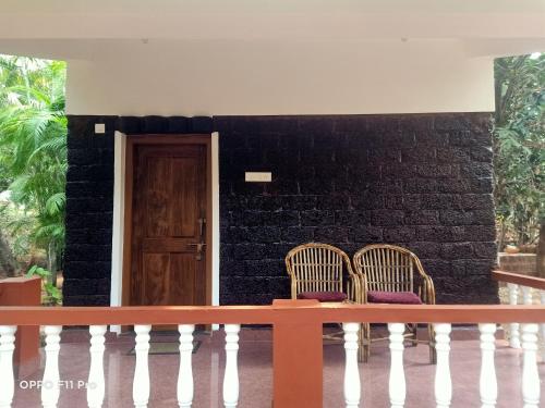 two chairs sitting in front of a brick wall at Namaste Yoga Farm in Gokarna
