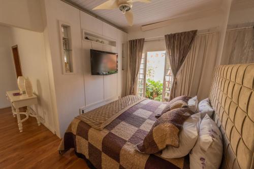 Schlafzimmer mit einem Bett und einem TV an der Wand in der Unterkunft Casa com WiFi e lazer em Campina Grande do Sul in Campina Grande do Sul