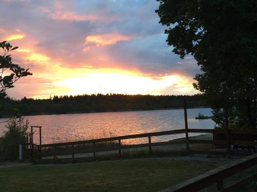 a sunset over a lake with benches and a fence at Hof van Sellingen in Sellingen
