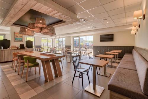 un restaurant avec des tables et des chaises en bois et des fenêtres dans l'établissement Campanile Saint Jean de Luz, à Saint-Jean-de-Luz