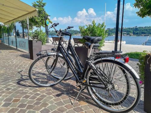 a bicycle is parked on a sidewalk near the water at Hotel Vigna in Salò