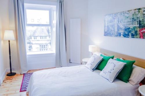um quarto com uma cama com almofadas verdes e brancas em Newly Furnished 2 Bedroom Apartment on Leith Walk em Edimburgo