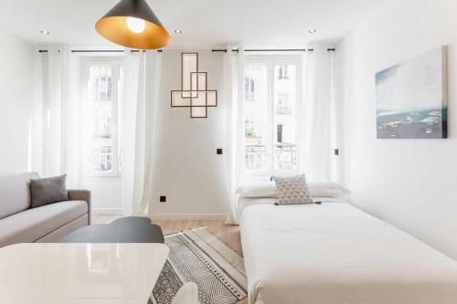a white living room with a couch and a table at Amazing 2 Bedroom Parisian flat in Paris