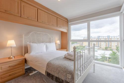 a bedroom with a bed and a large window at Bright Modern One-Bed with Stunning View of Thames in London