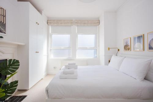 a white bedroom with a white bed and a window at Stylish & Modern 3 Bed Flat in NW London with Garden in London