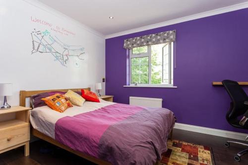 ロンドンにあるSpacious 3 Bedroom House with Garden in Bermondseyの紫色のベッドルーム(ベッド1台、窓付)