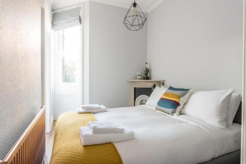 a bedroom with a white bed with towels on it at Bright 1 Bedroom Flat Minutes from the Beach and Trains in Brighton & Hove