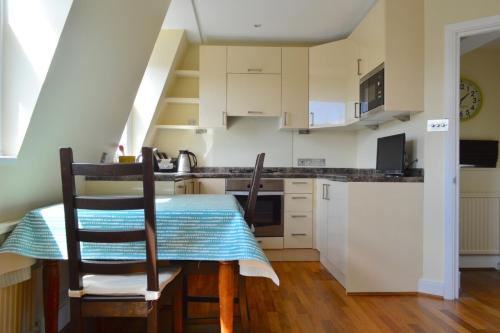 cocina con mesa, 2 sillas y mesa en Lovely Top Floor Flat in Leafy Fulham, en Londres