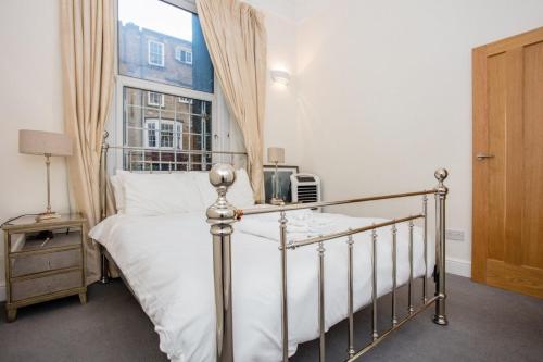 ロンドンにあるCosy 1 Bedroom Apartment Near Harrods Knightsbridgeのベッドルーム1室(白いシーツ付きのベッド1台、窓付)