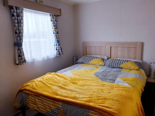 a bedroom with a bed with a yellow blanket on it at The Abi Joseph @Combe Haven in Hastings