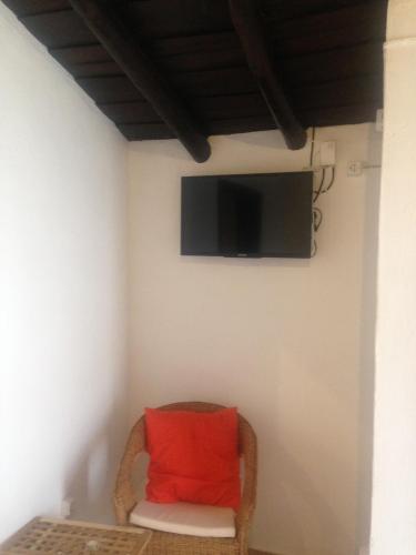 a red pillow sitting in a chair with a tv on a wall at Recanto na Planicie in Monsaraz