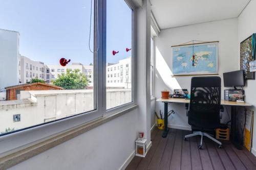 リスボンにあるCharming 2 bedroom apartment at Resteloのデスクと大きな窓のあるオフィス