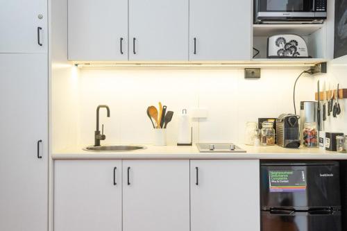 a kitchen with white cabinets and a sink at Boutique Studio Apartment at Potts Point in Sydney