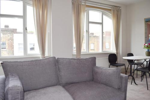 a living room with a couch and two windows at Stylish light-filled 1 Bedroom Flat In Hammersmith in London