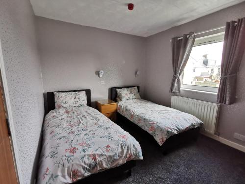 a small bedroom with two beds and a window at Whitehouse Guest House in Stirling