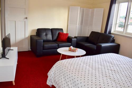 a room with a bed and a couch and a table at Comfortable 3 Bedroom Apartment In Trendy Haberfield in Sydney
