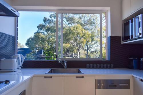 a kitchen with a sink and a large window at Sun-Drenched 1 Bed Studio Apartment In Newtown in Sydney