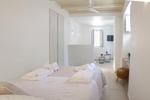 a white bedroom with a bed with white sheets and towels at La Maison de Marie Geraldine in Hydra