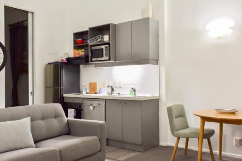 a living room with a couch and a kitchen at Cozy Queen Street 1 Bedroom flat in the Heart of Central Business District in Auckland