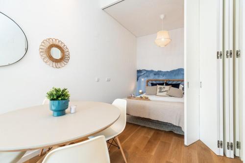 uma sala de jantar branca com uma mesa branca e uma cama em Spacious Studio in Lisbon em Lisboa
