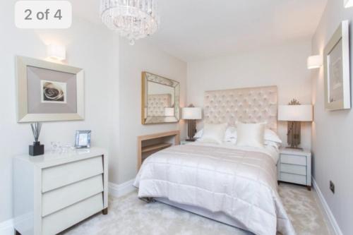 een witte slaapkamer met een bed en een kroonluchter bij Luxury Mayfair 2 Bedroom Apartment in Londen