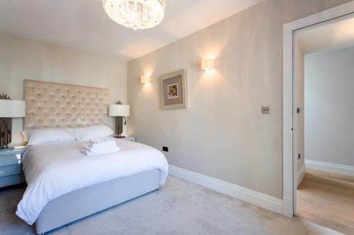 een witte slaapkamer met een groot bed en een kroonluchter bij Luxury Mayfair 2 Bedroom Apartment in Londen