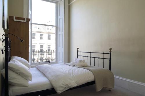 a bedroom with a bed with white sheets and a window at Grand New Town 2 Bedroom in Central Edinburgh in Edinburgh