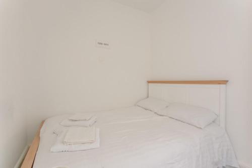 a white bed with white sheets and towels on it at Bright and Lovely 1 Bedroom Flat Belsize in London