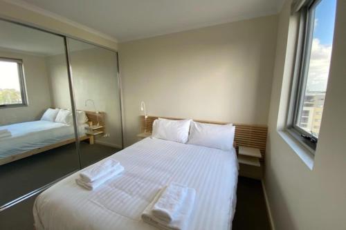a hotel room with a large white bed and a window at Stunning Two-Storey Apartment in Perth's CBD in Perth