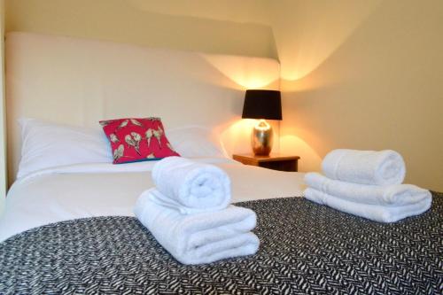 エディンバラにあるCosy Bright and Modern 1 Bedroom City Centre Flatのホテルルーム ベッドの上に白いタオルを用意しています。