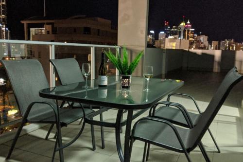 a glass table and chairs on a balcony at night at Stunning Two-Storey Apartment in Perth's CBD in Perth